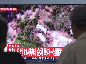 People watch a TV screen showing a satellite image of the Punggye-ri nuclear test site in North Korea during a news program at the Seoul Railway Station in Seoul, South Korea, Thursday, May 24, 2018. North Korea carried out what it said is the demolition of its nuclear test site Thursday, setting off a series of explosions over several hours in the presence of foreign journalists. The signs read: " North Korea demolishes nuclear test site at 11 AM."