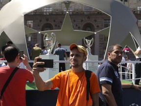 People take photographs next to the Champions League trophies at a fan zone in Kiev, Ukraine, Thursday, May 24, 2018. Liverpool will play Real Madrid in the Champions League Final on Saturday May 26 at the Olympiyski stadium in Kiev.