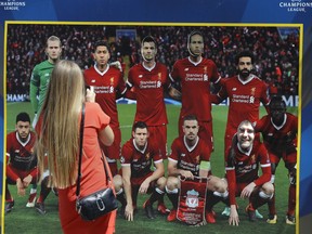 A woman takes a photo of a banner depicting Liverpool team at a fan-zone in Kiev, Ukraine, Thursday, May 24, 2018. Liverpool will play Real Madrid in the Champions League Final on May 26 at the Olympiyski stadium in Kiev.