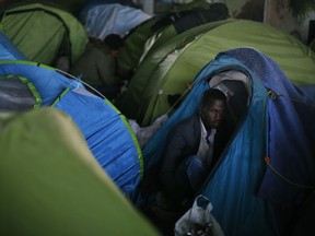 A migrant stands in his tent during the evacuation of a makeshift camp, in Paris, Wednesday, May 30, 2018. Authorities moved in early Wednesday to the so-called Millennaire tent camp on the city's edge alongside a canal used by joggers and cyclists. It is the largest of several around Paris. Two migrants drowned this month in canals along the encampments.