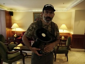 Opposition lawmaker Nikol Pashinian holds a megaphone during an interview with the Associated Press in Yerevan on Wednesday, May 2, 2018. Opposition protesters on Wednesday blocked the road leading from Armenia's capital, Yerevan, to its airport, as well as several subway stations and government ministries after Pashinian their leader called for a national strike.