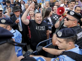 A protester shouts at riot police setting up fences during a protest outside the government headquarters in Bucharest, Romania, Saturday, May 12, 2018. Thousands gathered in the Romanian capital to demonstrate against a contentious judicial overhaul they say will make it harder to prosecute senior officials for graft, in a protest called "We want Europe, not a dictatorship".