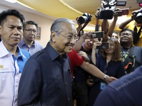 Malaysian Prime Minister Mahathir Mohamad, center, arrives for a press conference to announce his cabinet members in Petaling Jaya, Malaysia, Saturday, May 12, 2018. Mahathir said Friday he will form a lean cabinet with 10 core ministries and start the process of obtaining an immediate pardon for jailed opposition icon Anwar Ibrahim.