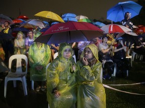 In this May 6, 2018 photo, supporters of former Malaysian strongman Mahathir Mohamad wait as rain pours during an election campaign in Kuala Lumpur, Malaysia. Malaysia's opposition parties have never come close to winning a majority of seats in a national election, even in 2013 when their total vote exceeded the ruling coalition. That year, the ruling National Front won 47 percent of votes but 60 percent of the seats in parliament. A similar result is likely in elections set for May 9 even if support for the opposition continues to increase.