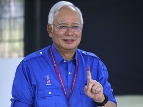 FILE - In this May 9, 2018, file photo, then Malaysian Prime Minister Najib Razak shows his finger marked with ink after voting at his hometown in Pekan, Pahang state, Malaysia. After 60 years of uninterrupted National Front rule, many Malaysians are optimistic they are ushering in an era of reform that echoes the democratic transformation of giant neighbor Indonesia two decades earlier. The difference, they hope, is that it will continue to be accomplished without setting their multiethnic country in flames. A grouping of progressive Southeast Asian lawmakers has hailed Najib's defeat as a "bright spot amid dark times" of rising authoritarianism across the region.