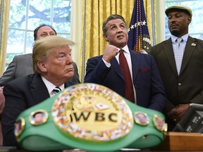 In this May 24, 2018 file photo, President Donald Trump, left, and heavyweight champion boxer, Lennox Lewis, right, watch as Sylvester Stallone gestures in the Oval Office of the White House in Washington, where Trump granted a posthumous pardon to Jack Johnson, boxing's first black heavyweight champion.
