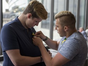 Humboldt Broncos bus crash survivor Kaleb Dahlgren, right, helps pin a ribbon on Xavier Labelle's shirt during their layover in Calgary before heading to Las Vegas for the NHL awards on June 18.