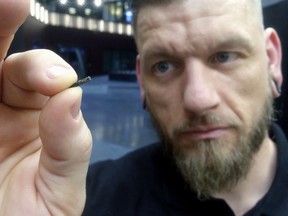 In this March 14, 2017, file photo, Jowan Osterlund from Biohax Sweden, holds a small microchip implant, similar to those implanted into workers at the Epicenter digital innovation business center during a party at the co-working space in central Stockholm.