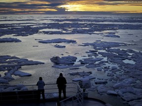 In this July 21, 2017 file photo, researchers look out from the Finnish icebreaker MSV Nordica as the sun sets over sea ice in the Victoria Strait along the Northwest Passage in the Canadian Arctic Archipelago.