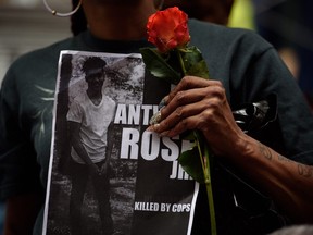 A woman holds a rose and a sign for Antwon Rose as she joins more than 200 people gathered for a rally to protest the fatal shooting of Rose at the Allegheny County Courthouse on June 21, 2018 in Pittsburgh, Pennsylvania. The rally comes in the aftermath of the fatal shooting of Antwon Rose by an East Pittsburgh police officer Tuesday night as the 17-year-old ran after being stopped by police in a vehicle suspected of being involved in an earlier shooting. The organizers called on Allegheny County District Attorney Stephen Zappala Jr. to bring criminal charges against the officer.