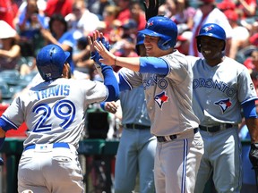 Devon Travis #29 of the Toronto Blue Jays is greeted at home by Justin Smoak #14, Curtis Granderson #18 and Aledmys Diaz #1 of the Toronto Blue Jays after hitting a three run home run in the second inning of the game off Felix Pena #64 of the Los Angeles Angels of Anaheim of Anaheim at Angel Stadium on June 24, 2018 in Anaheim, California.