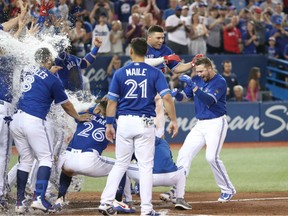 Justin Smoak is greeted at home plate by Blue Jays teammates after hitting a game-winning solo home run in the ninth inning against the Detroit Tigers at Rogers Centre on Saturday in Toronto.