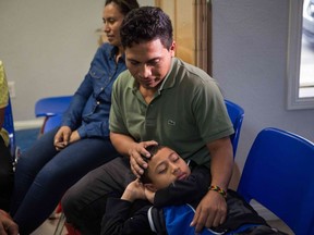 In this file photo taken on June 17, 2018 an immigrant from El Salvador and his 10-year-old son pass the time after being released from detention through "catch and release" immigration policy at a Catholic Charities relief centre in McAllen, Texas.