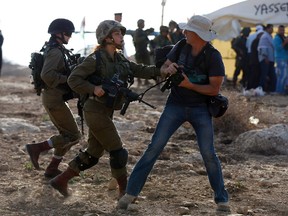 An Israeli soldier scuffles with an Israeli man during a demonstration by Palestinians and Israelis against the construction of Jewish settlements in the village of Ein al-Beida, north of the city of Nablus in the West Bank, on November 17, 2016.