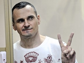 FILE - In this Tuesday, Aug. 25, 2015 file photo, Oleg Sentsov gestures as the verdict is delivered, as he stands behind bars at a court in Rostov-on-Don, Russia. A state news agency is quoting a Russian human rights official as saying that jailed Ukrainian filmmaker Oleg Sentsov is in satisfactory condition despite a month-long hunger strike, it was reported on Thursday, June 21, 2018. (AP Photo, file)