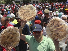 Jordanian protesters shout "bread" in front of the Labour Union offices in Amman, Jordan Wednesday, June 6, 2018. "Corruption equals hunger," is written in Arabic on loaves of bread.