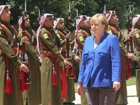 German Chancellor Angela Merkel reviews an honor guard upon her arrival at the Royal Palace in Amman, Jordan Thursday, June 21, 2018. German Chancellor Angela Merkel on Thursday visited Jordan, a major refugee host country, amid an escalating domestic conflict over migration that has shaken her coalition government.