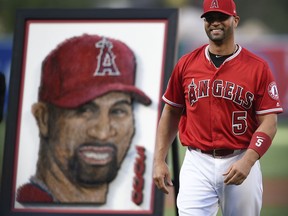 Los Angeles Angels' Albert Pujols smiles after throwing out the ceremonial first pitch following a ceremony in honor of his 3,000th career hit, at the team's baseball game against the Texas Rangers in Anaheim, Calif., Saturday, June 2, 2018.