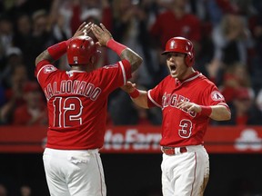 Los Angeles Angels' Ian Kinsler, right, and Martin Maldonado celebrate after they scored on a single by Mike Trout during the fifth inning of the team's baseball game against the Arizona Diamondbacks, Tuesday, June 19, 2018, in Anaheim, Calif.