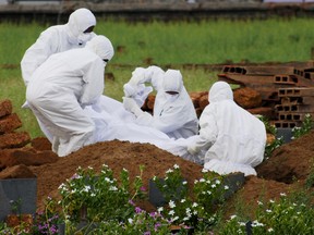 In this Thursday, May 24, 2018, photo, paramedics wear protective suits as a precautionary measure against the Nipah virus as they bury Valachekutti Mosa's body, died of the same virus, in Kozhikode, in the southern Indian state of Kerala.