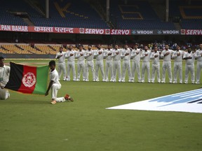 Members of Afghanistan cricket team stand for their national anthem before the start of the one-off test match against India in Bangalore, India, Thursday, June 14, 2018.