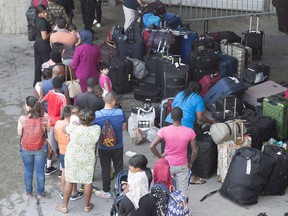 Asylum seekers line up to enter Olympic Stadium Friday, August 4, 2017 near Montreal, Quebec. Quebec, which has seen the majority of asylum seekers this year arriving through a forest path in Saint-Bernard-de-Lacolle, will receive $36 million. Ontario will get $11 million and Manitoba $3 million.