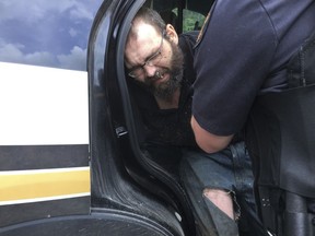 In this image released by the Tennessee Highway Patrol, Steven Joshua Wiggins is detained by officers, Friday, June 1, 2018, in Hickman County, Tenn. Wiggins, suspected in the fatal shooting of a Tennessee sheriff's deputy during a traffic stop, was arrested Friday after a two-day manhunt, authorities said.  (Tennessee Highway Patrol via AP)