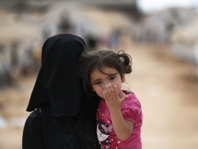 A Syrian woman carries a child in a squalid camp for internally displaced people in al-Bab, northern Syria, Tuesday, May 29, 2018. The population of the Turkish-controlled town has doubled in the last weeks to accommodate thousands who were displaced after the opposition surrendered in eastern Ghouta, outside Damascus. Al-Bab, whose population was about 7,000 when it was controlled by the Islamic State group until February 2017, has grown to about 300,000, according to Turkish officials, with most of those are displaced from other parts of Syria.