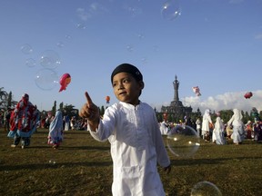 A Muslim boy plays with bubbles as he attends Eid al-Fitr prayers to mark the end of the holy fasting month of Ramadan in Bali, Indonesia, Friday, June 15, 2018.