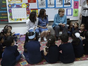 German Chancellor Angela Merkel, right, speaks with Lebanese and Syrian displaced students, during her visit to a Lebanese public school, where both students studying together, in Beirut, Lebanon, Friday, June 22, 2018. Merkel is visiting Jordan and Lebanon, both neighbors of war-torn Syria, amid an escalating domestic row over migration.