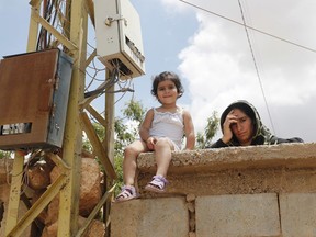 A Syrian refugee woman stands next to her daughter as she watches the visit of the Lebanese Foreign Minister Gibran Bassil to their refugee camp, in Arsal, near the border with Syria, east Lebanon, Wednesday, June 13, 2018. A public spat between the Lebanese government and the United Nation's refugee agency deepened Wednesday as Lebanon's caretaker foreign minister kept up his criticism, accusing the agency of discouraging Syrian refugees from returning home. Lebanon is home to more than a million Syrian refugees, or about a quarter of the country's population, putting a huge strain on the economy.