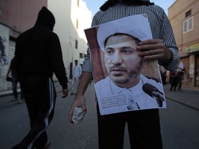 FILE- In this Saturday, Jan. 3, 2015 file photo, a Bahraini anti-government protester holding a stone and a picture of jailed Shiite cleric Sheikh Ali Salman, head of the opposition al-Wefaq political association, confronts police during clashes in Bilad Al Qadeem, Bahrain, a suburb of Manama. A prominent Shiite cleric in Bahrain who led a now-shuttered opposition party was acquitted Thursday, June 21, 2018 of spying charges with two colleagues, marking a rare victory for activists in the island kingdom amid a clampdown on all dissent.