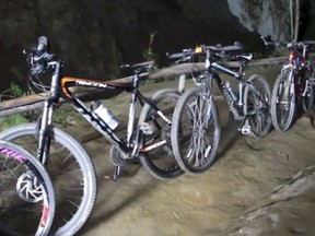 In this image made from video taken Sunday, June 24, 2018, bicycles left from a group of boys who went missing stand parked outside a deep cave in Chang Rai, northern Thailand. Officials say multiple attempts to locate the 12 boys and their soccer coach missing in a flooded cave in northern Thailand for nearly two days have failed, but that they will keep trying. (TPBS via AP)