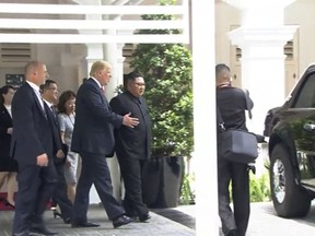 In this image made from video provided by Host Broadcaster Mediacorp Pte Ltd, U.S. President Donald Trump shows North Korean leader Kim Jong Un, center, his presidential vehicle outside the Capella Hotel in Singapore, Tuesday, June 12, 2018. (Host Broadcaster Mediacorp Pte Ltd via AP)