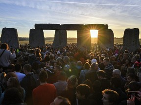 The sun rises through the stones at Stonehenge as crowds of people gather to celebrate the dawn of the longest day in the UK, in Wiltshire, England, Thursday June 21, 2018.