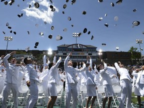 FILE - In this May 23, 2018, file photo, new ensigns toss their cadet covers into the air upon graduation from the United States Coast Guard Academy in New London, Conn. The academy, like many other predominantly white institutions, has wrestled with how to make minorities feel more welcome. It's chief diversity officer, Aram deKoven, said that the academy does not tolerate discrimination of any kind and several initiatives are under way to improve the climate.