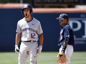 Washington's Kaiser Weiss, left, celebrates his two-run double as Cal State Fullerton's Hank LoForte watches during the ninth inning of Game 1 of an NCAA college baseball tournament super regional Friday, June 8, 2018, in Fullerton, Calif. Washington won 8-5.