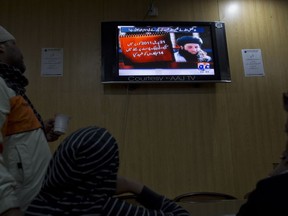 FILE - In this Nov. 7, 2013 file photo, people watch a news report on TV about newly selected leader of Pakistani Taliban leader Mullah Fazlullah at a coffee shop in Islamabad, Pakistan. An Afghan defense ministry official says Friday, June 15, 2018 a US drone strike in northeastern Kunar province killed Pakistan Taliban chief Mullah Fazlullah. Pakistan has been hunting Fazlullah for several years and has repeatedly said he was plotting attacks on Pakistan from safe havens in Afghanistan. The Arabic on the TV news report reads, "On April 21, 2011, fourteen troops were killed in an attack on a checkpoint in Dir."
