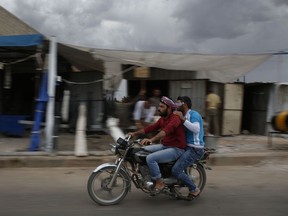 In this Tuesday, May 29, 2018 photo, men ride a motorcycle in al-Bab, northern Syria. Turkey is growing long-term roots in its northern Syrian enclave, nearly two years after its troops moved in, modeling the zone on its own towns and bringing in its own administrators and military, financial and security institutions. Turkey aims to keep out its nemesis, the U.S.-backed Syrian Kurdish militia known as the YPG.