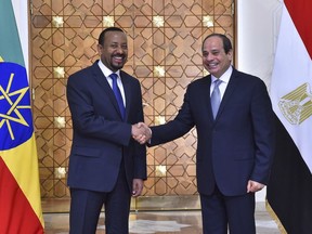 In this Sunday, June 10, 2018 photo, provided by Egypt's state news agency, MENA, Egyptian President Abdel-Fattah el-Sissi, right, shakes hands with Ethiopian Prime Minister Abiy Ahmed, in Cairo, Egypt. Egypt released 32 Ethiopian prisoners during a visit by the country's prime minister, in which he vowed that Ethiopia will not reduce Egypt's share of Nile waters, as his country works to complete what will be Africa's largest hydroelectric dam, officials said Monday. (MENA via AP)