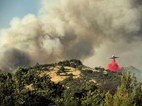 An air tanker drops retardant on a wildfire above the Spring Lakes community on Sunday, June 24, 2018., near Clearlake Oaks, Calif. Wind-driven wildfires destroyed buildings and threatened hundreds of others Sunday as they raced across dry brush in rural Northern California.