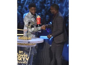 In this Saturday, June 16, 2018, photo, Chadwick Boseman, left, gives his best hero award for his role in "Black Panther" to James Shaw Jr., who is credited with saving lives during a shooting at a Waffle House in Antioch, Tenn., at the MTV Movie and TV Awards at the Barker Hangar in Santa Monica, Calif.