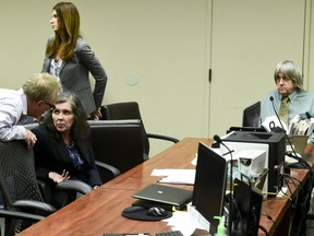 FILE - In this May 4, 2018, file photo, defendant Louise Anna Turpin, second left, talks with an investigator as her husband David Allen Turpin, right, looks on during a court appearance in Riverside, Calif. David and Louise Turpin are scheduled to appear for a preliminary hearing on Wednesday, June 20, 2018, in Riverside County Superior Court. A judge is set to hear testimony from law enforcement officers and consider whether authorities have amassed sufficient evidence for the Turpins to stand trial. They've pleaded not guilty to torture, child abuse and other charges.