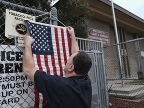 Election assistant Wayne Martin hangs an American flag outside a polling station at Robert F. Kennedy Elementary School in Los Angeles on Tuesday, June 5, 2018. Traffic at polling stations was expected to be light because people voted in advance.