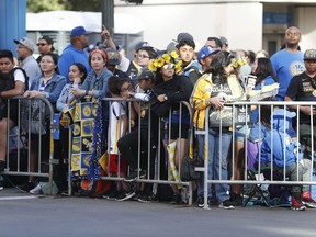 Fans wait for the parade to start in honor of the Golden State Warriors, Tuesday, June 12, 2018, in Oakland, Calif., to celebrate the team's NBA basketball championship.