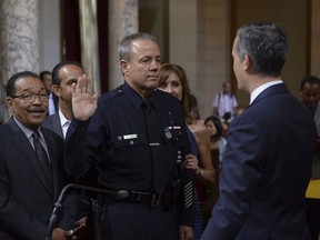 Michel Moore, a 36-year veteran of the Los Angeles Police Department, is sworn in by Los Angeles Mayor Eric Garcewtti, right in Los Angeles City Council Chambers as council members, from left, Herb Wesson, Mitch Englander, Nury Martinez, look on Wednesday, June 27, 2018. Moore replaces Charlie Beck, who retired after more than 40 years with the LAPD.