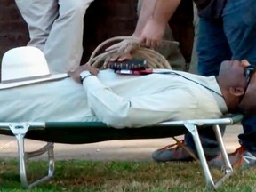 FILE - In this April 17, 2018, file image from video provided by KTHV-TV, a death penalty protester outside the Arkansas governor's mansion in Little Rock prepares to tie rope around Pulaski County Circuit Judge Wendell Griffen who is laying on a cot in protest of executions. An Arkansas panel that disciplines judges said Friday, June 8, 2018, that Griffen violated some judicial rules by attending a similar protest ahead of a series of Arkansas executions in 2017. (KTHV/TEGNA Inc. via AP, File)