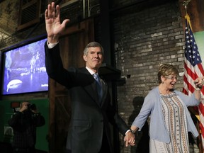 FILE - In this June 5, 2018, file photo, Fred Hubbell waves while holding hands with his wife, Charlotte, during a rally in Des Moines, Iowa. Hubbell, a former life insurance executive whose family wealth in Des Moines dates back to the mid-1800s, won the Democratic nomination Tuesday, June 5. Gov. Kim Reynolds and party leaders were quick to question how voters could trust a candidate who was born into a rich family.