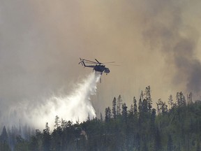 In this Tuesday, June 12, 2018 photo, smoke of a wildfire covers the Buffalo Mountain area, west of Silverthorne and north of Frisco, Colo. A fast-moving brush fire destroyed homes in the Utah tourist town of Moab, while several thousand people in Colorado and Wyoming fled multiple wildfires scorching the drought-stricken U.S. West on Wednesday.