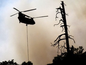 In this Tuesday, June 12, 2018, photo, smoke envelops a helicopter as it is used to battle a wildfire near Durango, Colo.